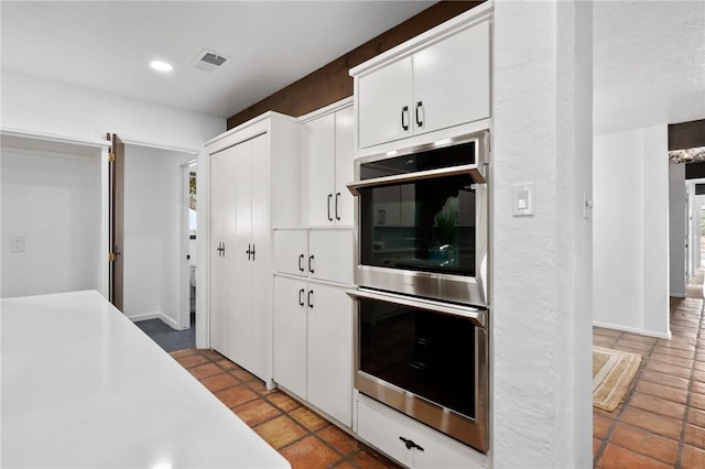 kitchen featuring tile patterned flooring, white cabinetry, and double oven