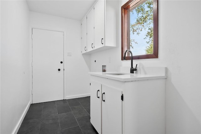 laundry room featuring washer hookup, cabinets, dark tile patterned floors, and sink