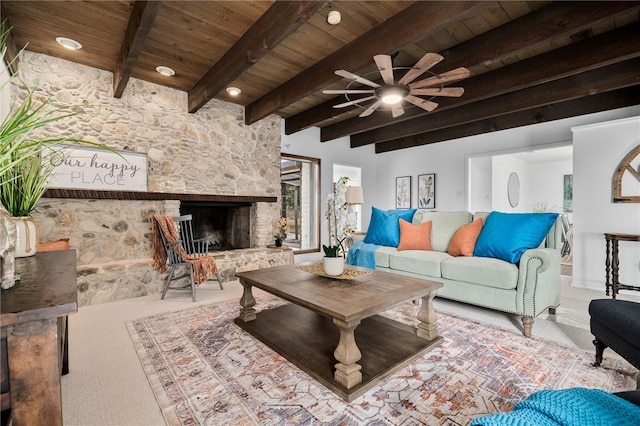 living room featuring carpet, wooden ceiling, a stone fireplace, ceiling fan, and beam ceiling