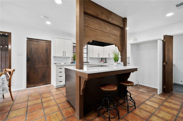 kitchen with white cabinets, decorative backsplash, and a kitchen bar