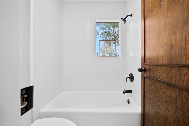 bathroom with toilet and tiled shower / bath