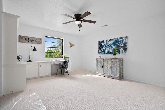 office space with ceiling fan, light colored carpet, and built in desk