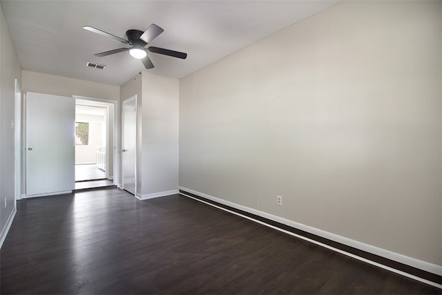 spare room featuring baseboards, ceiling fan, visible vents, and dark wood-type flooring