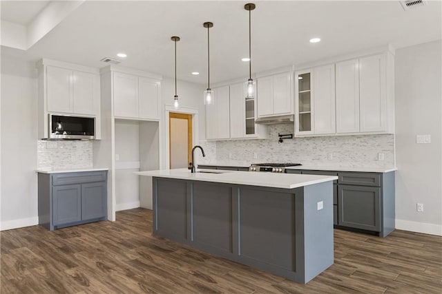 6218 Sadie St, Corpus Christi, TX 78415 - kitchen with stainless steel microwave, tasteful backsplash, white cabinetry, a center island with sink, and dark wood-style flooring