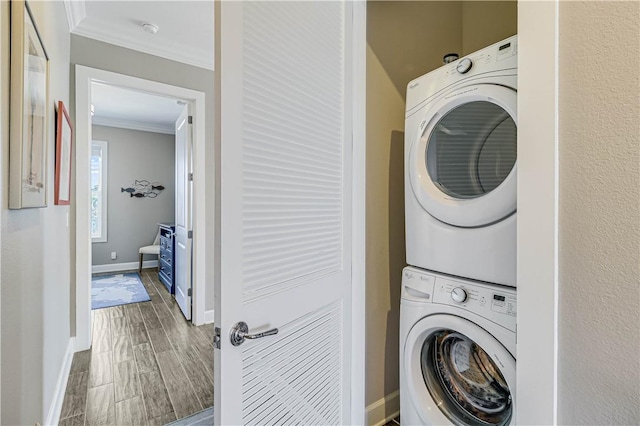 washroom featuring ornamental molding and stacked washer and dryer