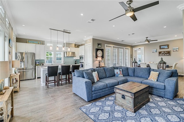 living room with ceiling fan, crown molding, and sink