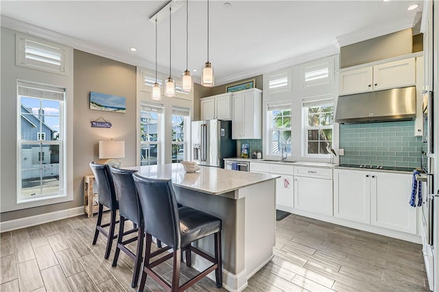 kitchen with white cabinetry, a center island, sink, stainless steel appliances, and backsplash