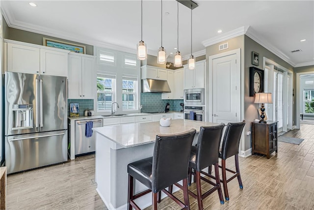 kitchen featuring white cabinetry, hanging light fixtures, a kitchen bar, a kitchen island, and appliances with stainless steel finishes