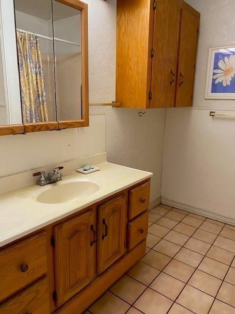 bathroom with tile patterned flooring, walk in shower, and vanity