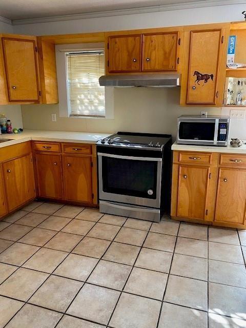 kitchen with light tile patterned floors, ornamental molding, and stainless steel appliances