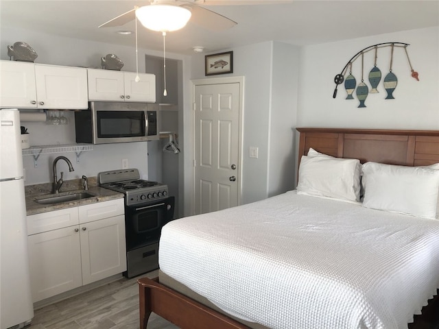 bedroom featuring ceiling fan, sink, light hardwood / wood-style flooring, and white refrigerator