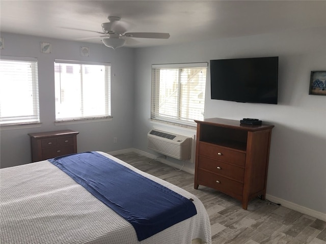 bedroom featuring ceiling fan, light hardwood / wood-style floors, a wall mounted AC, and multiple windows