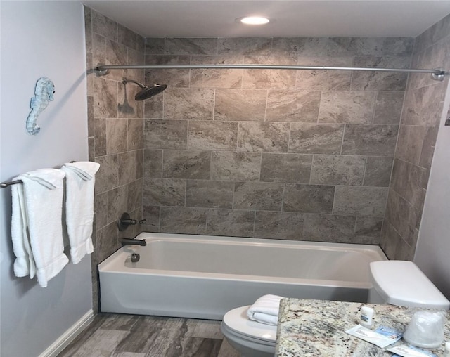 bathroom with tiled shower / bath combo, hardwood / wood-style flooring, and toilet