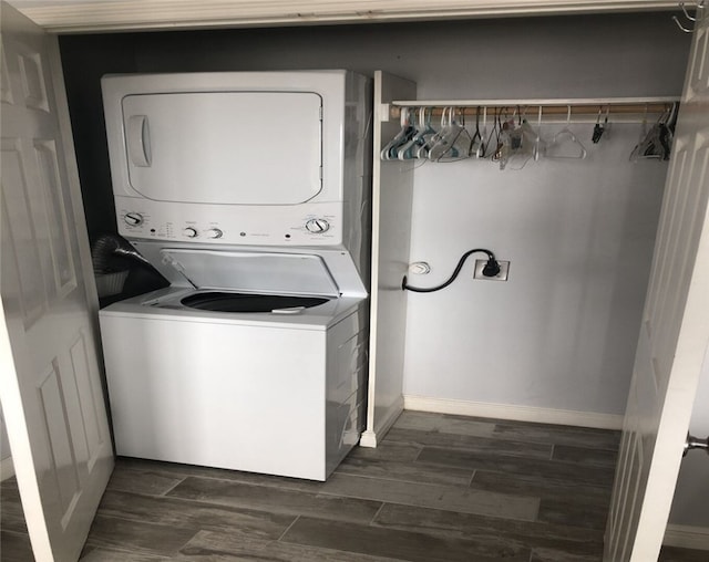 clothes washing area featuring dark hardwood / wood-style flooring and stacked washer and clothes dryer