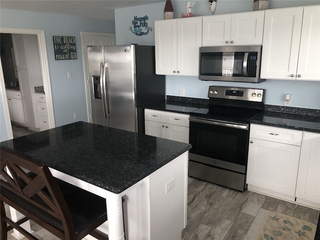 kitchen with appliances with stainless steel finishes, white cabinetry, and hardwood / wood-style floors