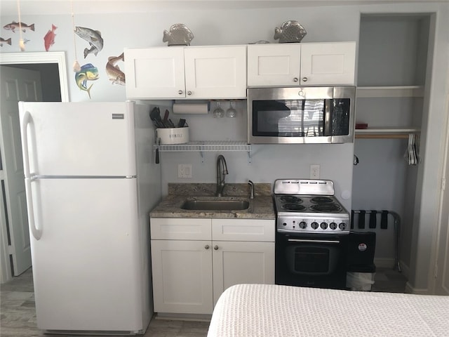 kitchen featuring sink, white cabinets, wood-type flooring, and appliances with stainless steel finishes