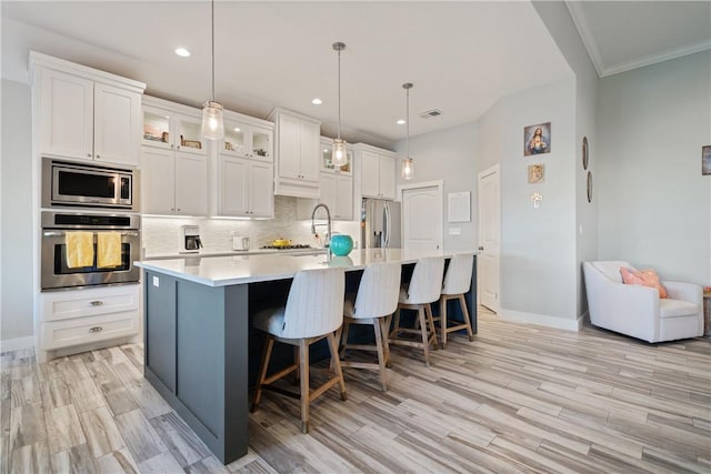 kitchen featuring stainless steel appliances, a spacious island, light countertops, backsplash, and white cabinets