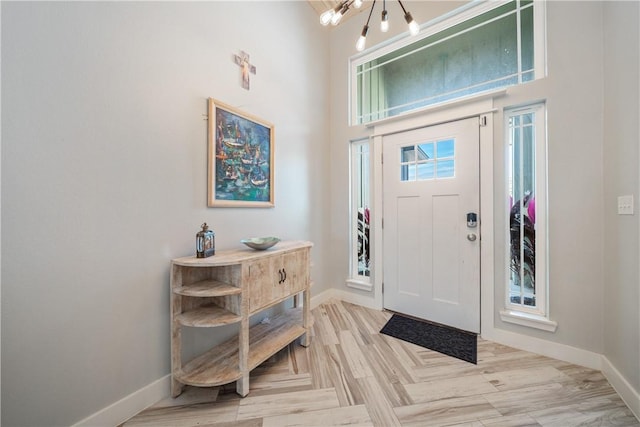 entrance foyer featuring parquet flooring, a high ceiling, and baseboards