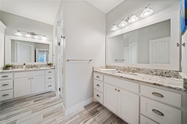 bathroom with two vanities, a sink, baseboards, and wood finished floors