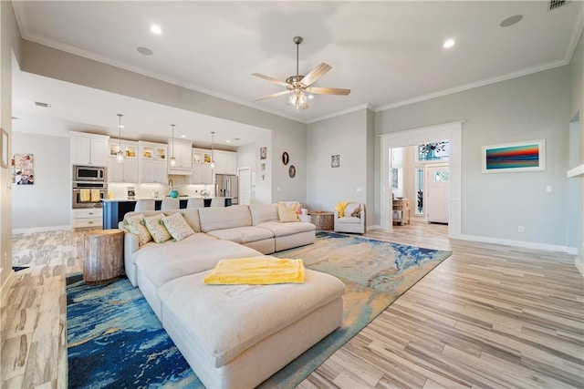 living area with light wood-type flooring, baseboards, and ornamental molding