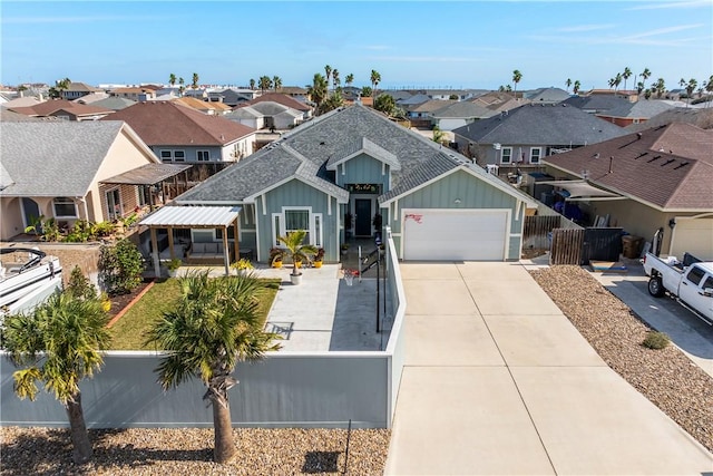 view of front of property with driveway, a shingled roof, a fenced front yard, a residential view, and board and batten siding