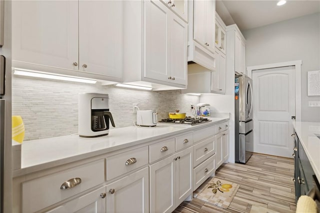 kitchen featuring tasteful backsplash, white cabinets, and light countertops