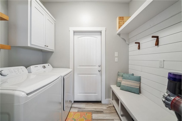 washroom with cabinet space, light wood finished floors, and washing machine and clothes dryer