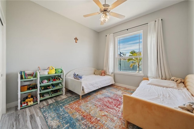 bedroom with ceiling fan, baseboards, and wood finished floors