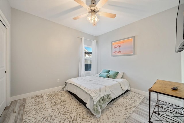 bedroom featuring light wood-style floors, a ceiling fan, baseboards, and a closet