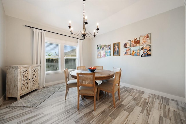 dining room featuring light wood-style floors, a notable chandelier, and baseboards