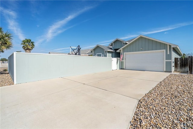 exterior space with a garage, fence, board and batten siding, and concrete driveway