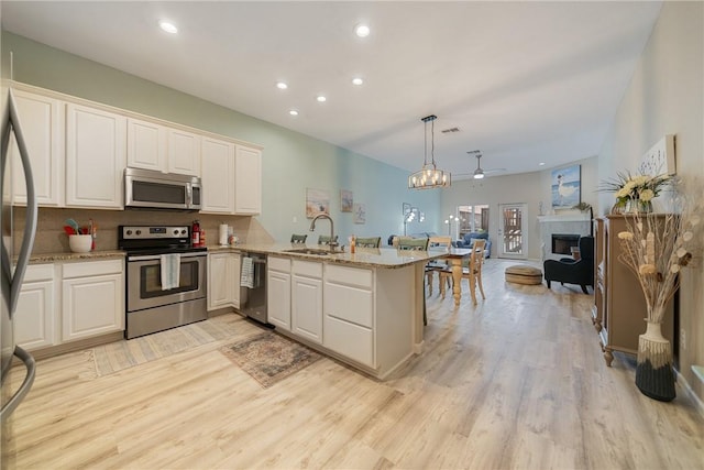 15414 Salt Cay Ct Unit 5E, Corpus Christi, TX 78418 - kitchen featuring a sink, a peninsula, light wood-style flooring, backsplash, and appliances with stainless steel finishes