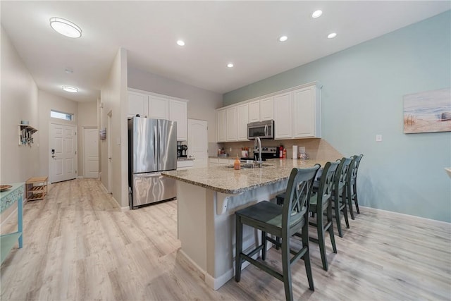 15414 Salt Cay Ct Unit 5E, Corpus Christi, TX 78418 - kitchen featuring a peninsula, stainless steel appliances, a breakfast bar area, light wood finished floors, and white cabinetry