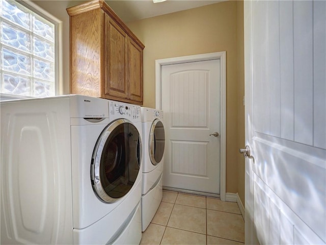 clothes washing area with baseboards, cabinet space, light tile patterned floors, and washing machine and dryer
