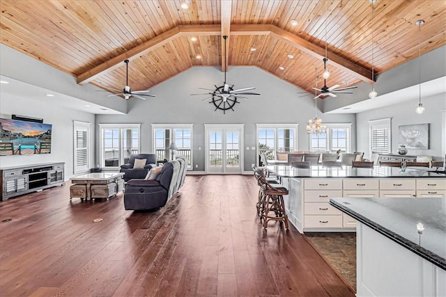 kitchen with dark hardwood / wood-style flooring, wood ceiling, a breakfast bar, decorative light fixtures, and white cabinetry