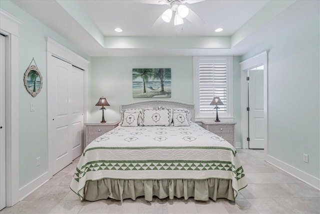 bedroom with a tray ceiling, a closet, and ceiling fan