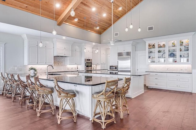 kitchen featuring built in appliances, high vaulted ceiling, hanging light fixtures, and wooden ceiling