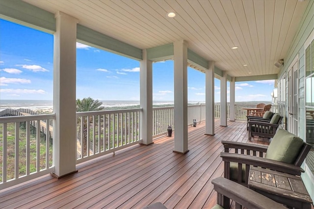 wooden deck featuring a water view and a beach view