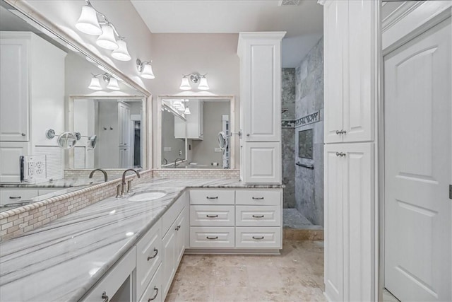 bathroom with a tile shower and vanity