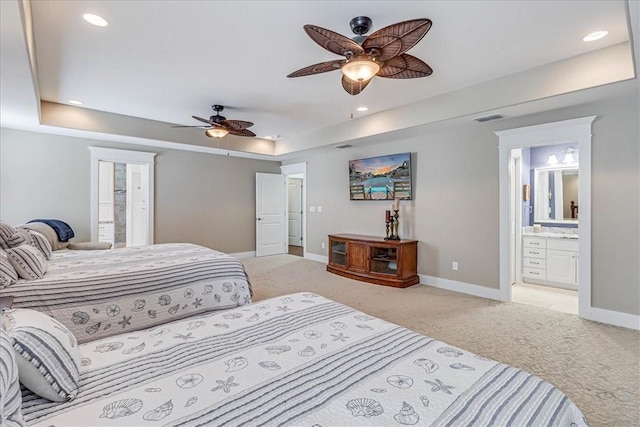 carpeted bedroom featuring connected bathroom, a tray ceiling, and ceiling fan