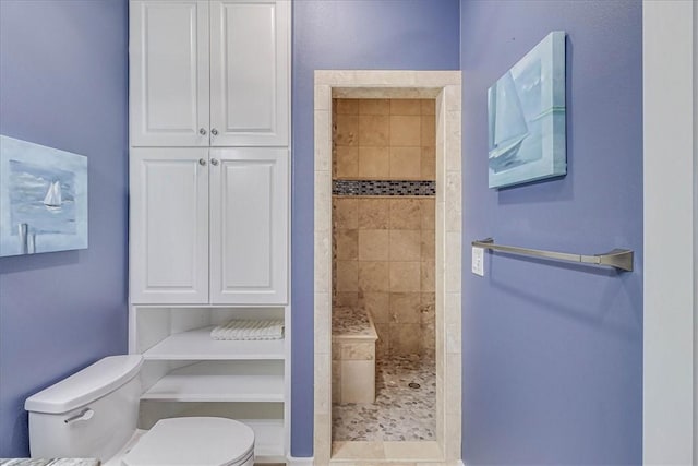 bathroom featuring toilet and a tile shower