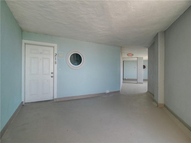 5973 State Highway 361 Unit 218, Port Aransas, TX 78373 - empty room featuring concrete floors, baseboards, and a textured ceiling