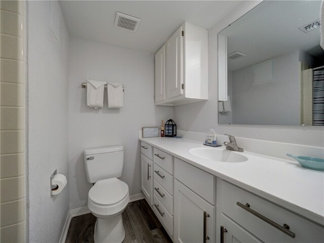 bathroom with toilet, vanity, and wood-type flooring