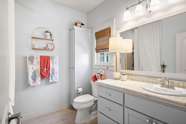 bathroom featuring vanity, wood finished floors, toilet, and baseboards