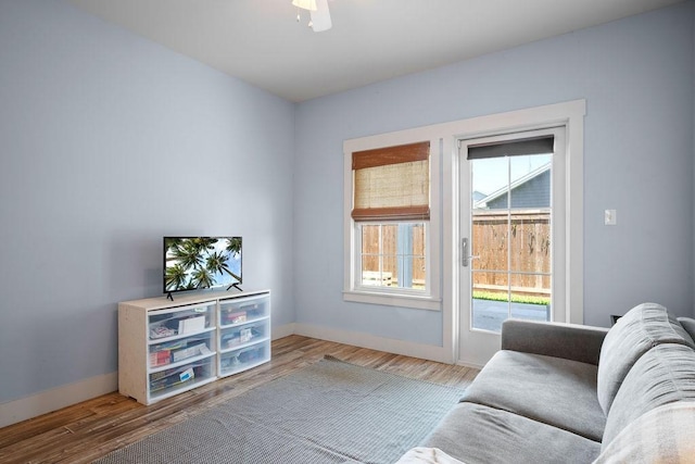 living room with a ceiling fan, baseboards, and wood finished floors