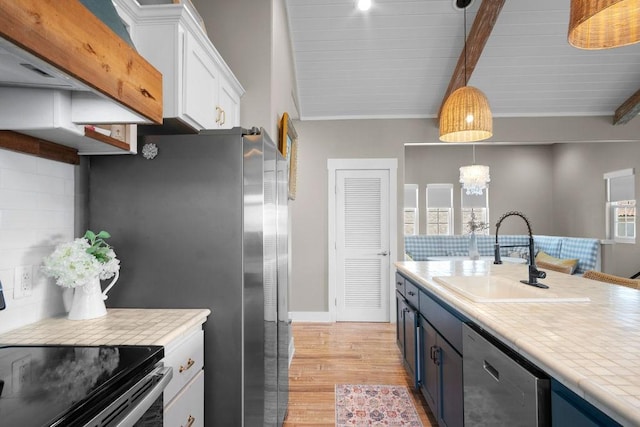 kitchen featuring stainless steel appliances, a sink, white cabinetry, light countertops, and light wood-type flooring