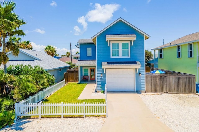 view of front facade with driveway, fence private yard, an attached garage, and a front yard