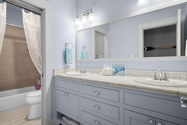 full bathroom featuring double vanity, wood finished floors, a sink, and toilet