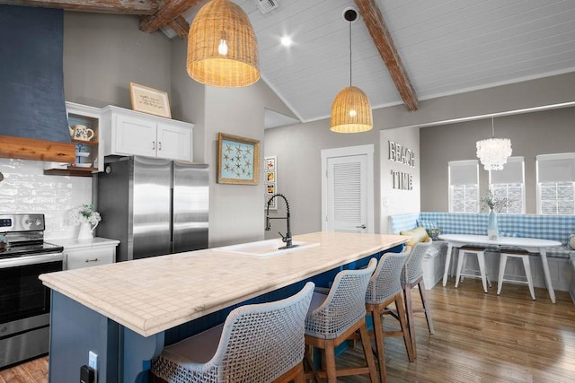 kitchen featuring stainless steel appliances, wood finished floors, a sink, backsplash, and open shelves