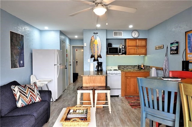 kitchen featuring hardwood / wood-style flooring, white appliances, and ceiling fan